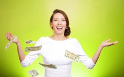 Closeup portrait super excited, laughing young woman who just won lots of money, trying to catch, throw dollar bills in air, isolated green background. Positive emotion, facial expression, feelings