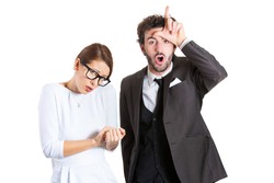 Closeup portrait couple, business people. Bully husband, man standing upfront, angry, giving bully sign with hand, shy, timid wife, nerdy woman with glasses, isolated white background. Human emotions