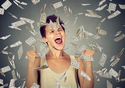 Happy young man going crazy screaming super excited. Ecstatic guy celebrates success under money rain falling down dollar bills banknotes isolated gray background. Financial freedom concept