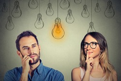 Cognitive skills ability concept, male vs female. Young man and woman looking at bright light bulb isolated on gray wall background