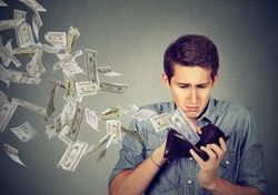 Sad man looking at his wallet with money dollar banknotes flying out away 