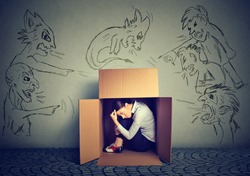 Bad evil men pointing at stressed woman. Desperate scared businesswoman hiding inside a box isolated on grey wall background. Negative human emotions face expression feelings life perception