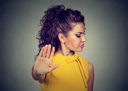 Closeup portrait annoyed angry woman with bad attitude giving talk to hand gesture with palm outward isolated gray wall background. Negative human emotion face expression feeling body language