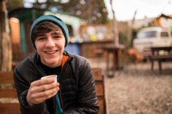 Young man enjoying a delicious coffee at an outdoor food truck stand in Patagonia, Argentina, during his winter vacation.