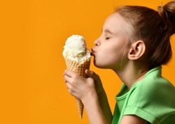 Pretty baby girl kid kiss vanilla ice cream in waffles cone on yellow background and show thumbs up sign with free text copy space