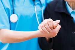 Caring nurse or doctor holding elderly lady's hand with care.