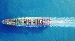 a Large container ship is leaving the port full loaded with containers and cargo - aerial - top down view