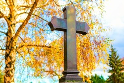 Black granite cross on the graveyard . Black cross on headstone . Autumn in cemetery 