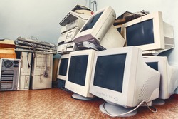 pile of old unused computers and vintage CRT monitors
