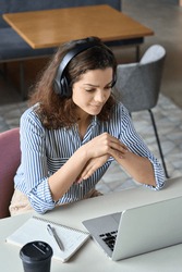Hispanic girl college student wearing headphones watching distance online learning web class, remote university webinar or having talk on laptop video call virtual meeting seminar at home or campus.