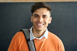 Portrait of young happy smiling Indian latin Hispanic high school college university student standing in classroom on black board background looking at camera. Headshot. Close up.