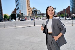 Smiling confident beautiful Asian young woman entrepreneur, professional businesswoman manager or saleswoman wearing business suit holding tablet standing on city street.