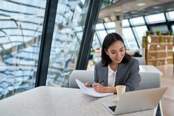 Young Asian business woman employee or executive manager using computer looking at laptop and talking leading hybrid conference remote video call virtual meeting or online interview working in