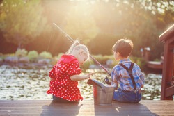 Two kids boy and girl fishing in a river on a wood pontoon