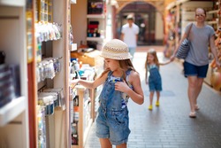 the child, a little girl chooses Souvenirs in a street shop at the resort hotel. a seaside holiday in the summer.