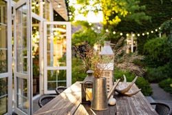 table for lunch outside in the garden in the courtyard with the lights of a country house at sunset. landscape design in the cottage.