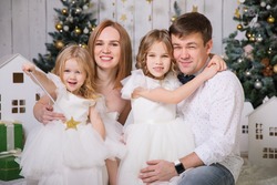 family with two daughters in Christmas decorations. happy and fun holidays. new year vacations. traditional annual photo shoot.