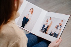 top view. woman watches photobook from photo shoot of family. storage of photos in photo album. work of designer, photographer and printer. memory of important moments of life