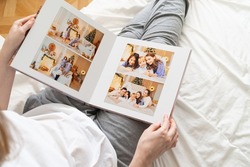 top view. a woman holds a photobook while sitting in bed. family photo shoot. professional printing of photos and albums in the printing, photo laboratory. photographer and designer services. memory.