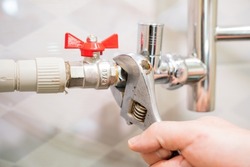 A male plumber repairs the pipes of the heated towel rail in the bathroom. replacement and maintenance of plumbing. handyman service. small business.