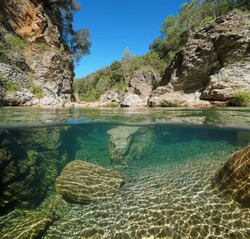 Wild river with rocks over and underwater, split view half above and below water surface, La Muga, Catalonia, Spain