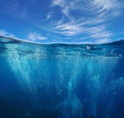 Seascape, air bubbles underwater sea and blue sky with cloud, split view over and under water surface, Mediterranean, France