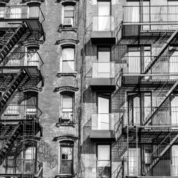 A fire escape of an apartment building in New York city. Graphical black and white image.