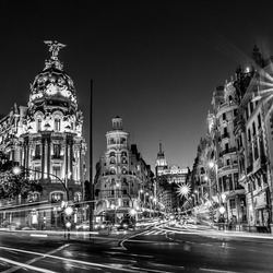 Rays of traffic lights on Gran via street, main shopping street in Madrid at night. Spain, Europe. Black and white photo.