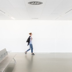 Motion blur of woman walking at contemporary white empty hallway.