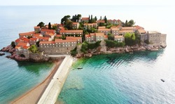 Amazing sunset aerial top drone view of Sveti Stefan island with historical town. Top down view of picturesque little island in Adriatic Sea located in Montenegro. Famous tourist attraction on Balkan.