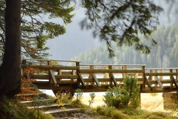 View of beauty wooden foot bridge near glacial Black Lake in National Park Durmitor, Montenegro. Mountain landscape on sunny autumn day. Durmitor is listed in the UNESCO World Heritage.