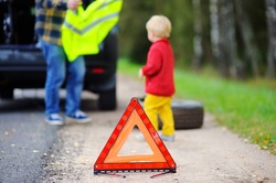 Father clothes yellow safety vest on his toddler son. Vehicle breakdown on travel trip