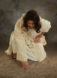 Jesus using his finger to white in the sand