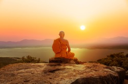 Buddhist monk in meditation at beautiful sunset or sunrise background on high mountain