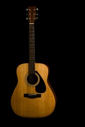 Acoustic guitar on black background with copy space