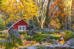 Red cottages in a garden with rocks and autumn leaves