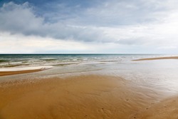 Sand beach with the ocean in the horizon and the storm clouds in the sky