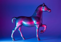 Horse figurine with neon blue and pink illumination background. Future warfare conceptual backdrop.