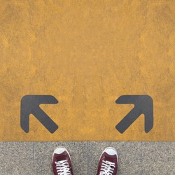 Pair of shoes standing on a road with two grey arrow on the yellow background