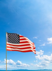 Flag of United States of America (USA) waving in the wind with blue sky and cloud on a sunny day