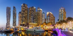Dubai Marina and Harbour skyline architecture wealth luxury travel with yacht boat at night panorama in United Arab Emirates modern
