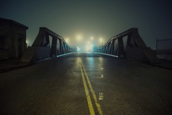 Dramatic industrial vintage river road bridge street scene at night with illuminating fog in Chicago.