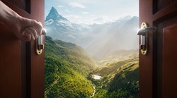 hand opens empty room door to nature and mountains