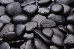 Black pebbles for texture and background Shining smooth natural beach stones or rocks