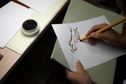A calligrapher writing with pen and ink. man hands writing arabic calligraphy with ink. Arabic and Persian calligraphy. Written in Farsi, 