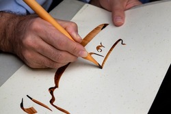 A calligrapher writing with pen and ink. man hands writing arabic calligraphy with ink. Arabic and Persian calligraphy. Writing Nastaliq calligraphy. 