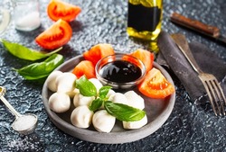 Caprese salad. Healthy meal with cherry tomatoes, mozzarella balls, spices, fresh rocket and basil. Home made, tasty food. Symbolic image.