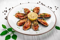 Baked mussels with cheese on plate. Mussels baked in shells with cheese and garlic. Serving food in a restaurant. Photo for the menu
