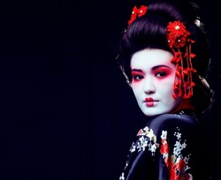 young pretty real geisha in kimono with sakura and decoration on black background