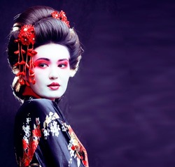 young pretty real geisha in kimono with sakura and decoration on black background